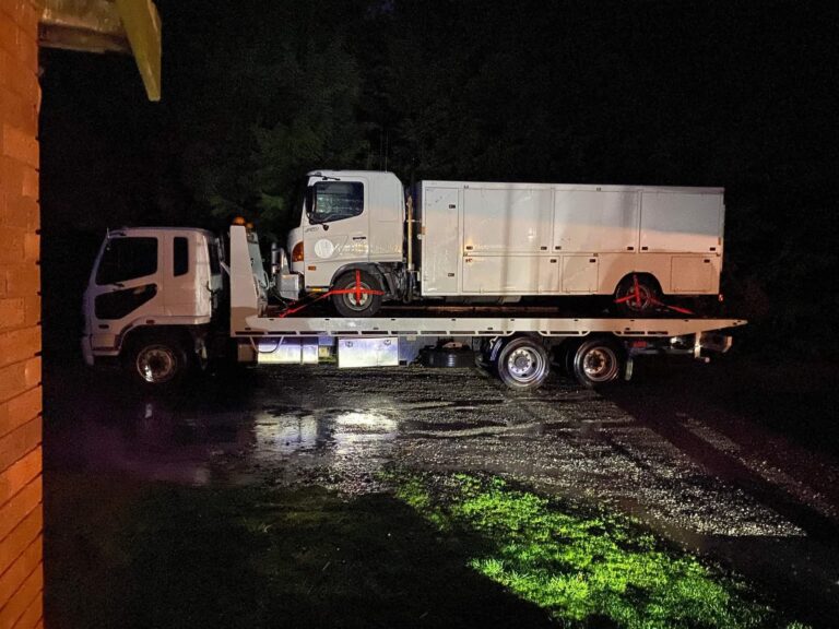 Tow truck carrying a vehicle at night, 24/7 towing Tasmania